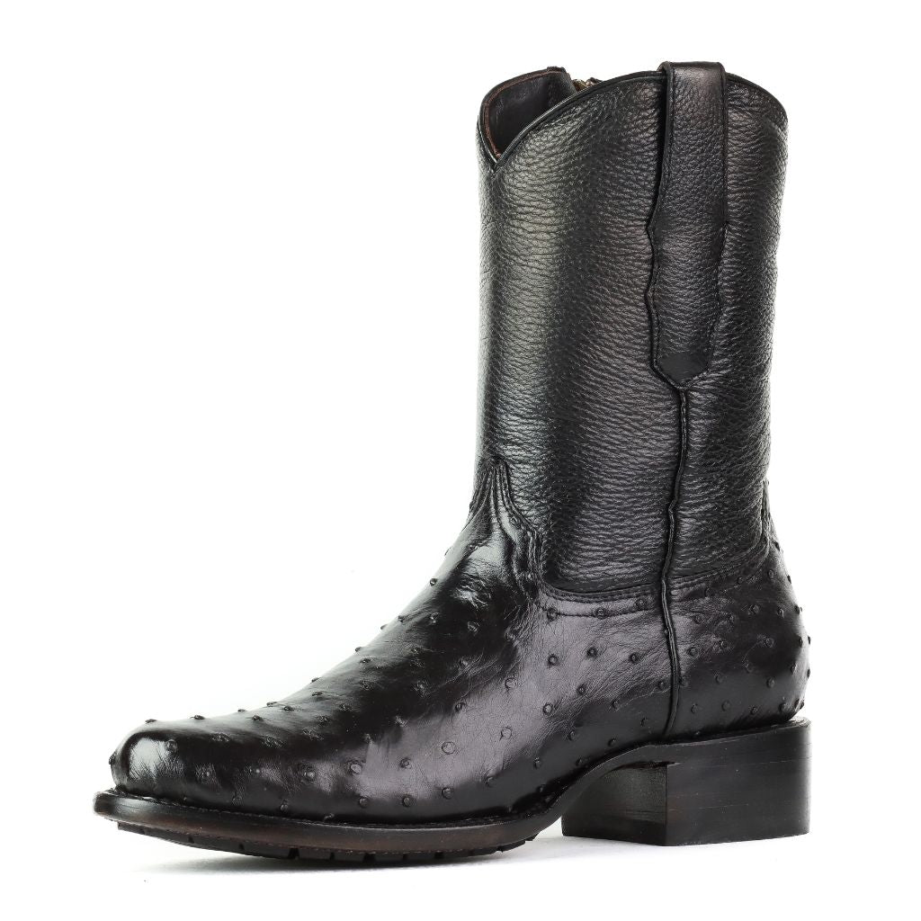 Vista lateral de la bota negra mostrando su textura de piel exótica.