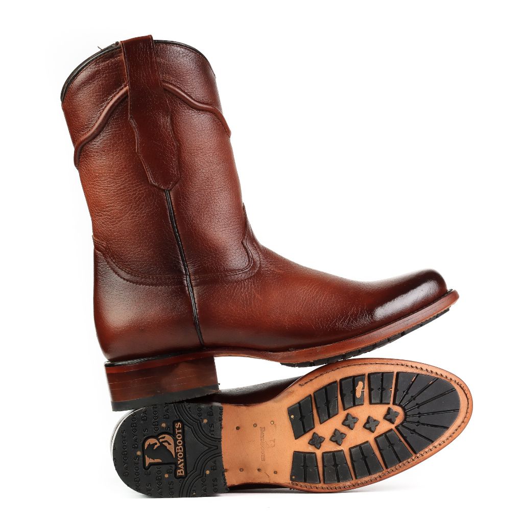 Bota inclinada destacando la suela con injertos de goma y el tacón.