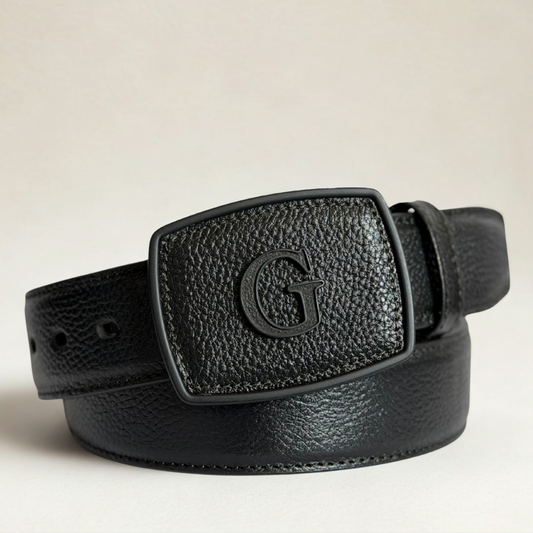 Cinto negro en piel de venado con hebilla negra y letra “G”.